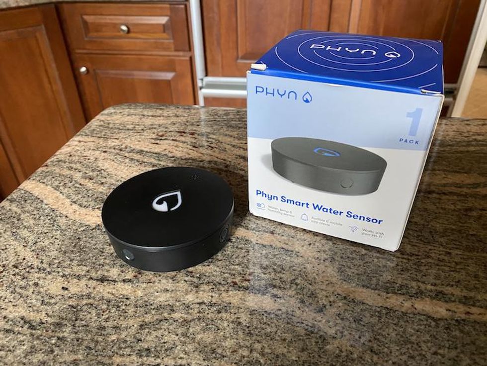 Phyn Smart Water Sensor and box on a countertop.