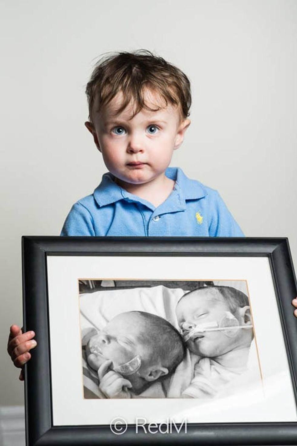 a  young boy holds a black and white photograph of himself and his deceased twin sister as premature babies