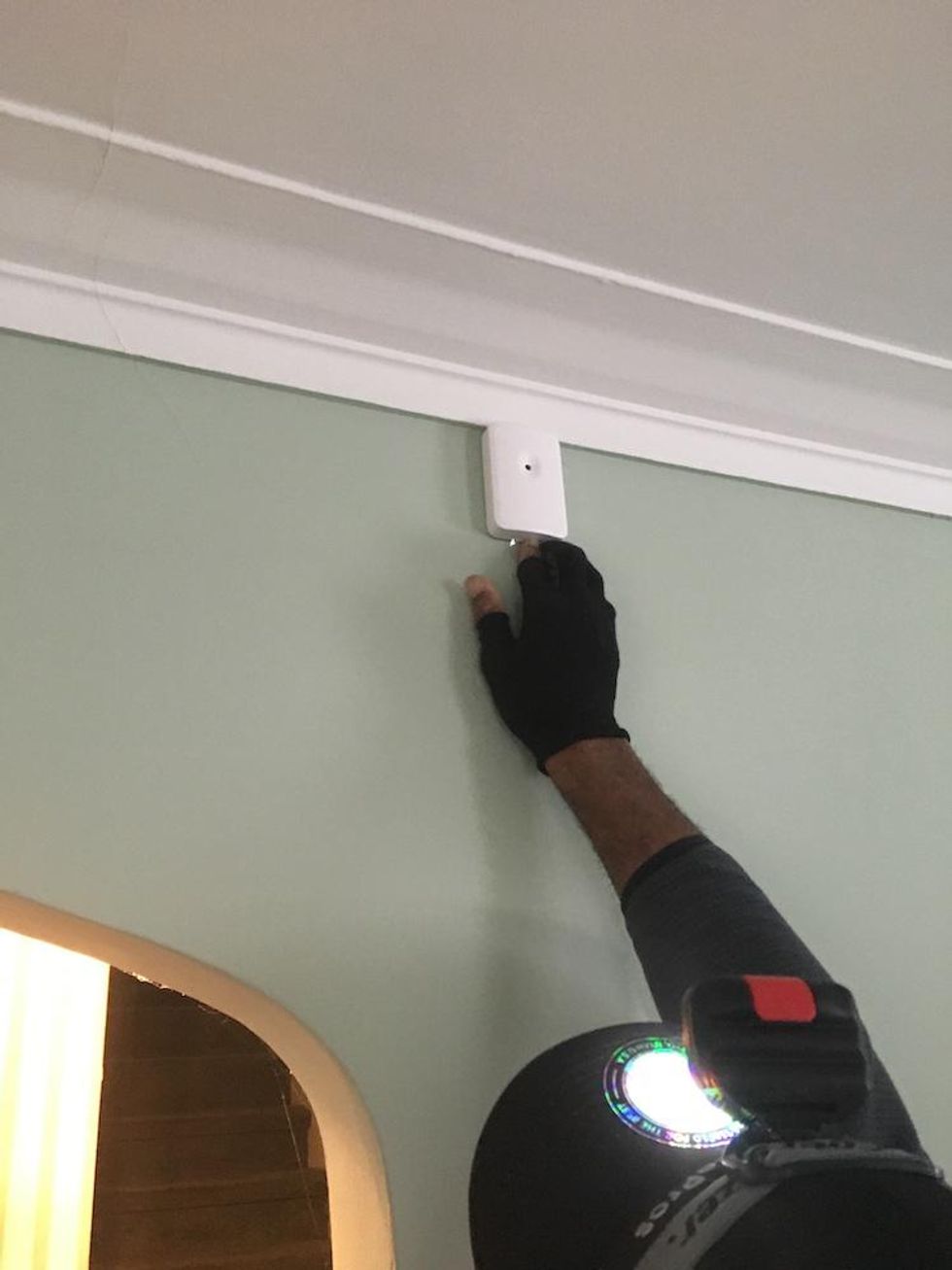 A glass break sensor being installed in a room by a Vivint installer.