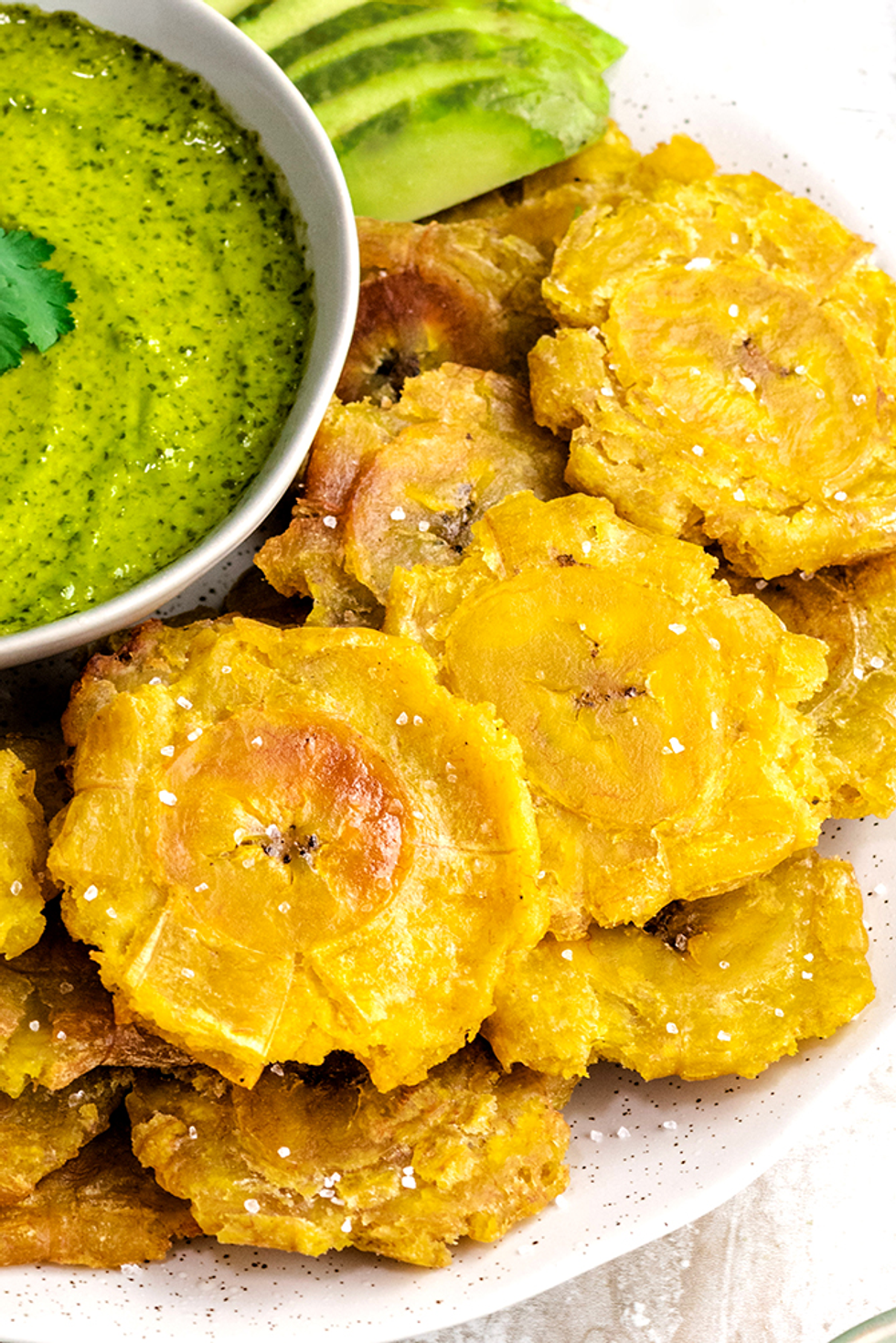 tostones on a plate with avocado and caldo