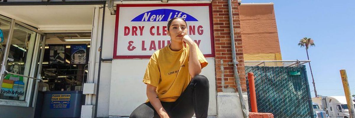 latina woman kneeling in front of a dry cleaning and laundry business