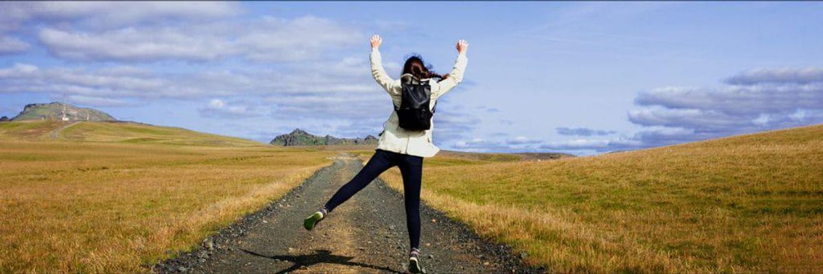 Photo of woman jumping on a hiking trail.