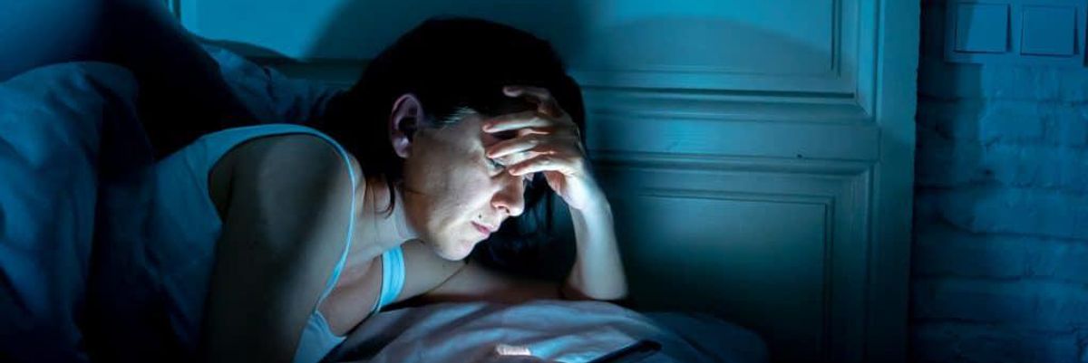 Woman scrolling through her phone in bed.