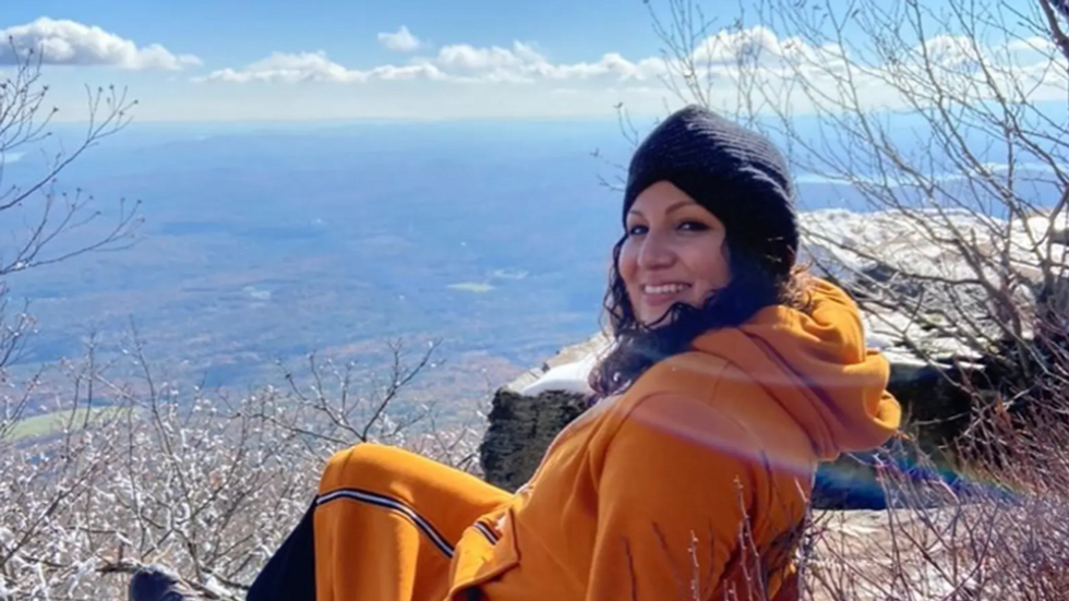 woman sitting at a high peak overlooking a view below