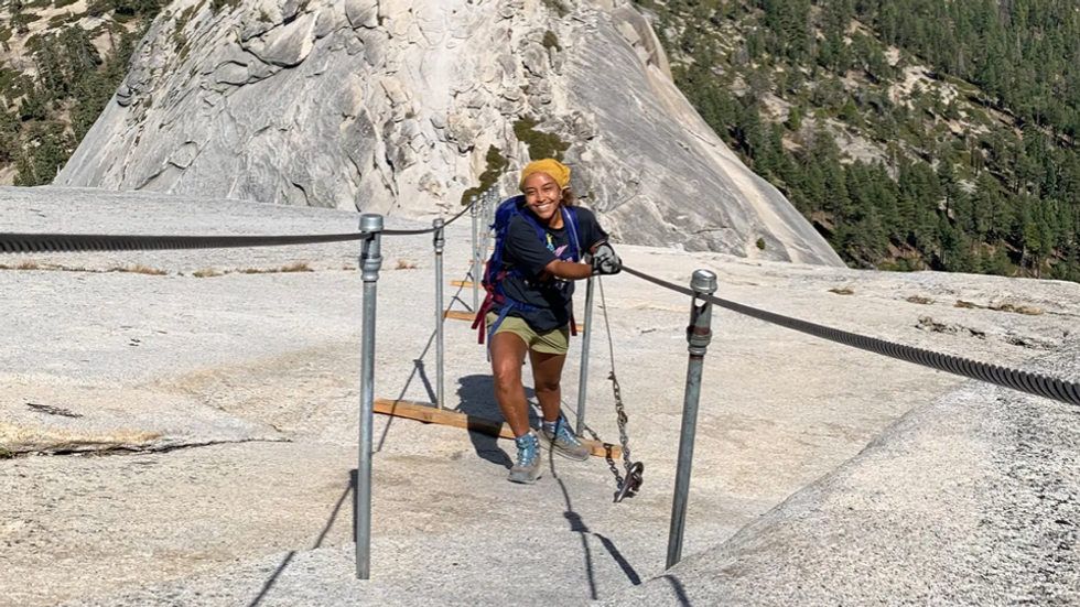 woman climbing up mountain using guardrail