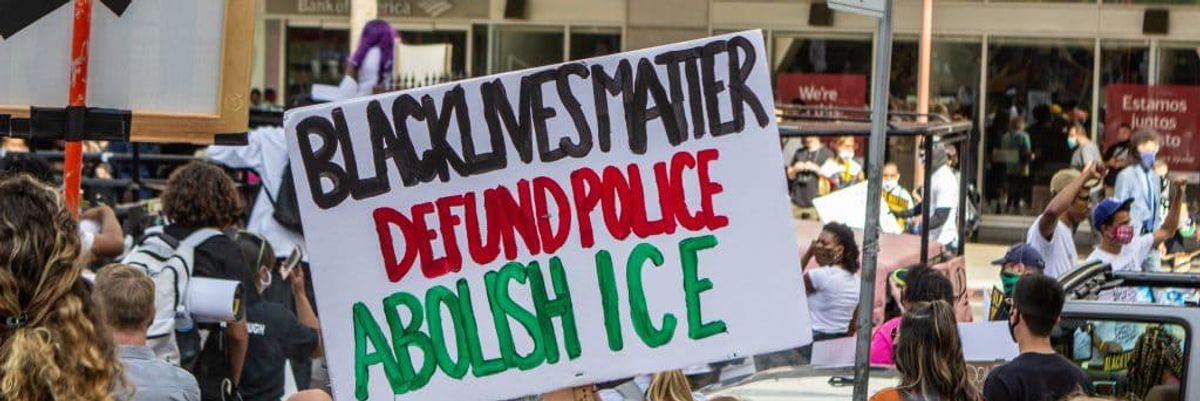 Sign that says "Black lives matter defund the police abolish ICE" 