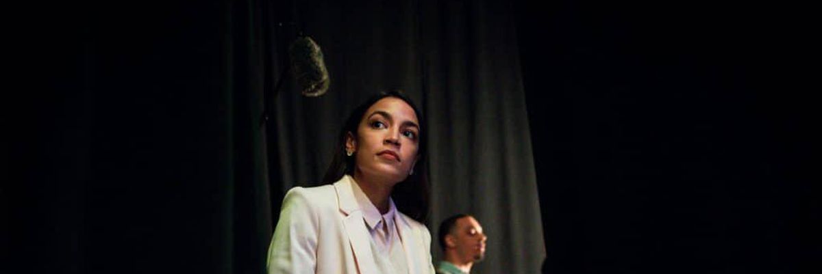 photo of woman, Alexandria Ocasio-Cortez, sitting in white suit