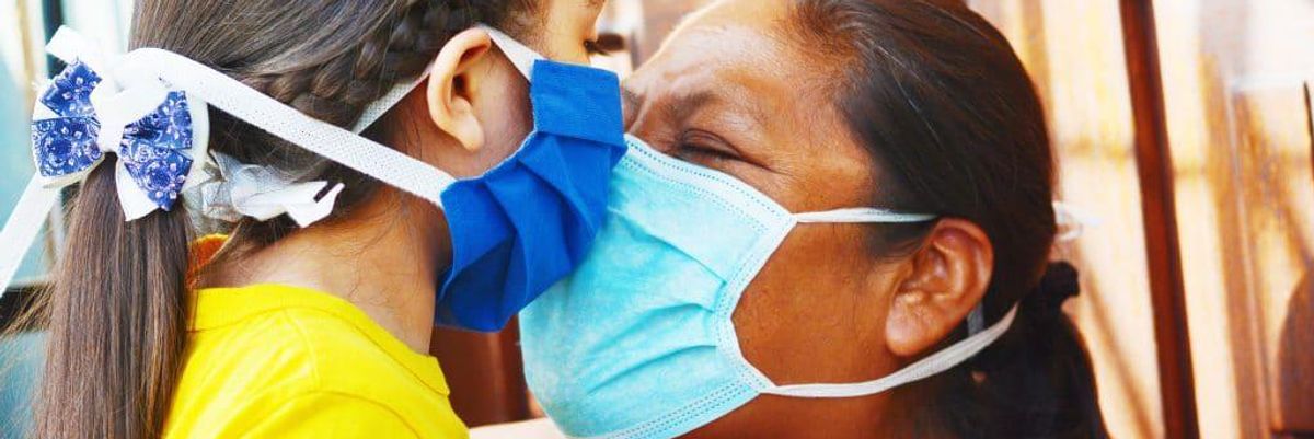 image of daughter and mother embracing face to face through masks