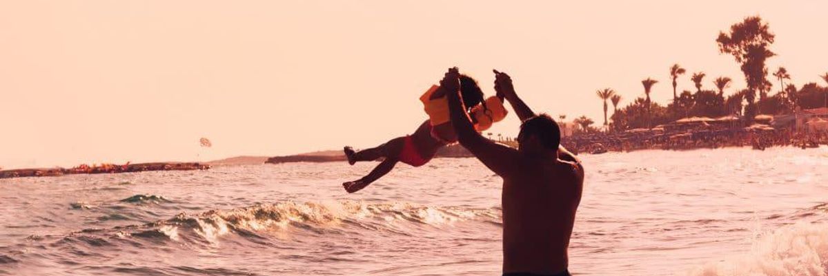 Father lifting his daughter up at the beach.