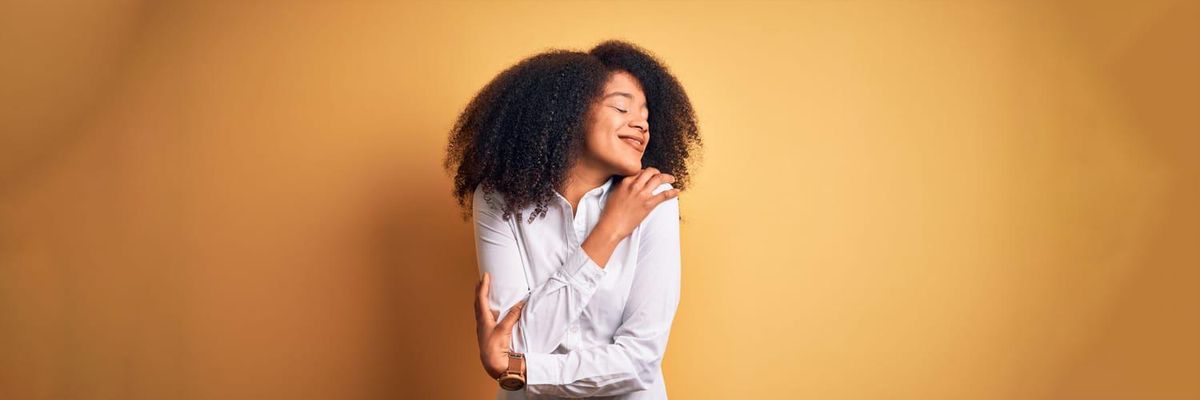 A Black woman hugs herself