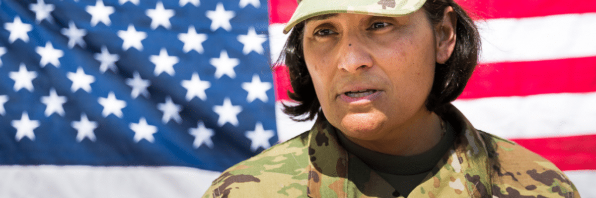 Army member standing in front of the American flag.