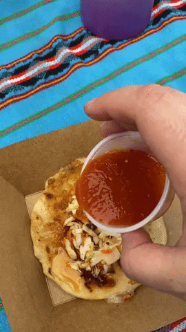 Putting toppings on a pupusa.