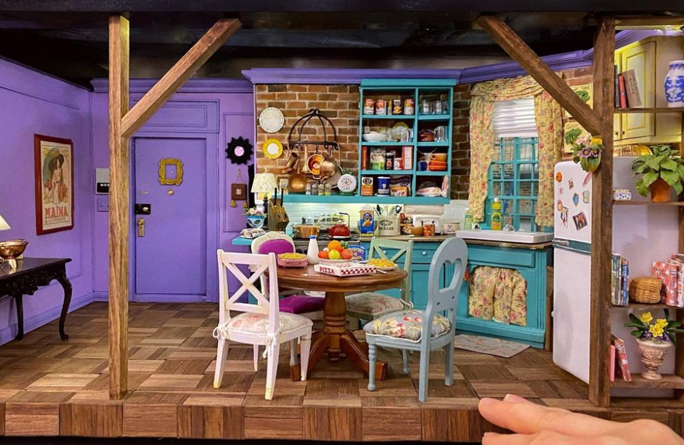 a miniature version of Monica's apartment from Friends next to someone's hand for scale. 