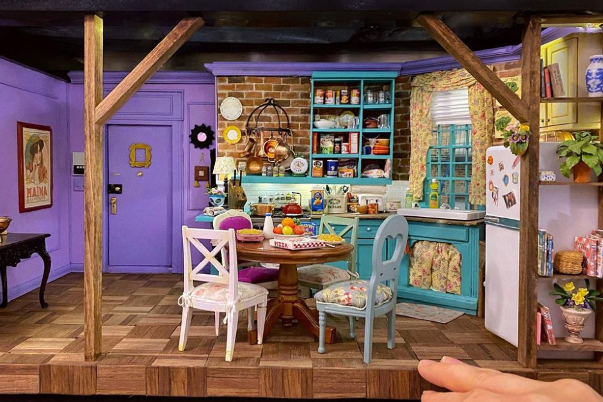 a miniature version of Monica's apartment from Friends next to someone's hand for scale.