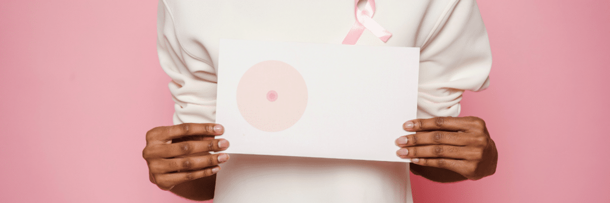 Woman holding up a sign with a breast cancer ribbon.