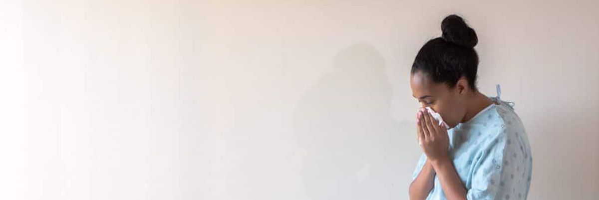 Pregnant woman blowing her nose.