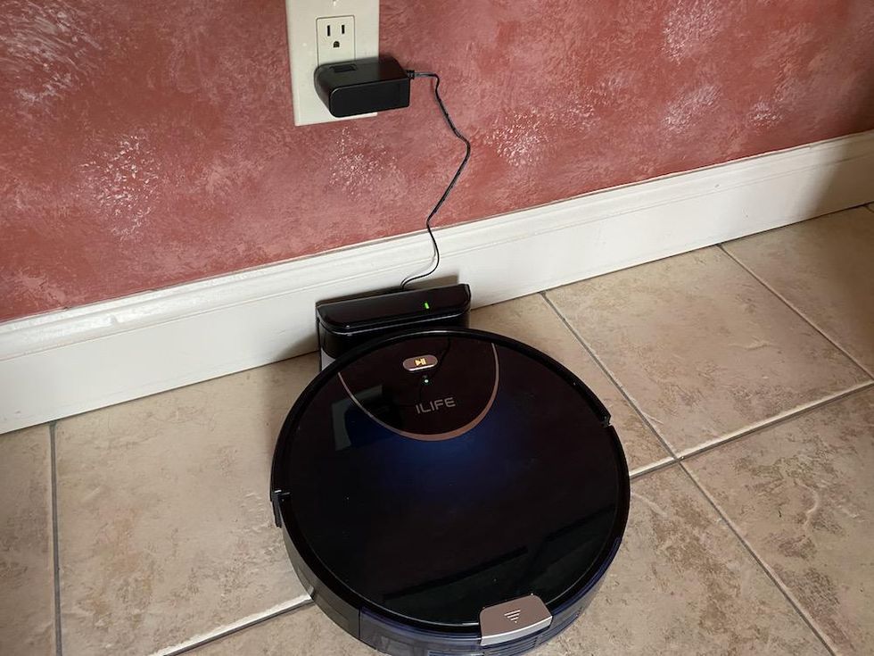 a photo of iLife Robot Vacuum on its charging station on the floor