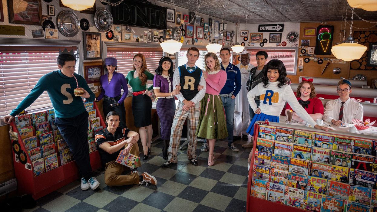 The cast of Riverdale poses next to racks of comic books at Pop's