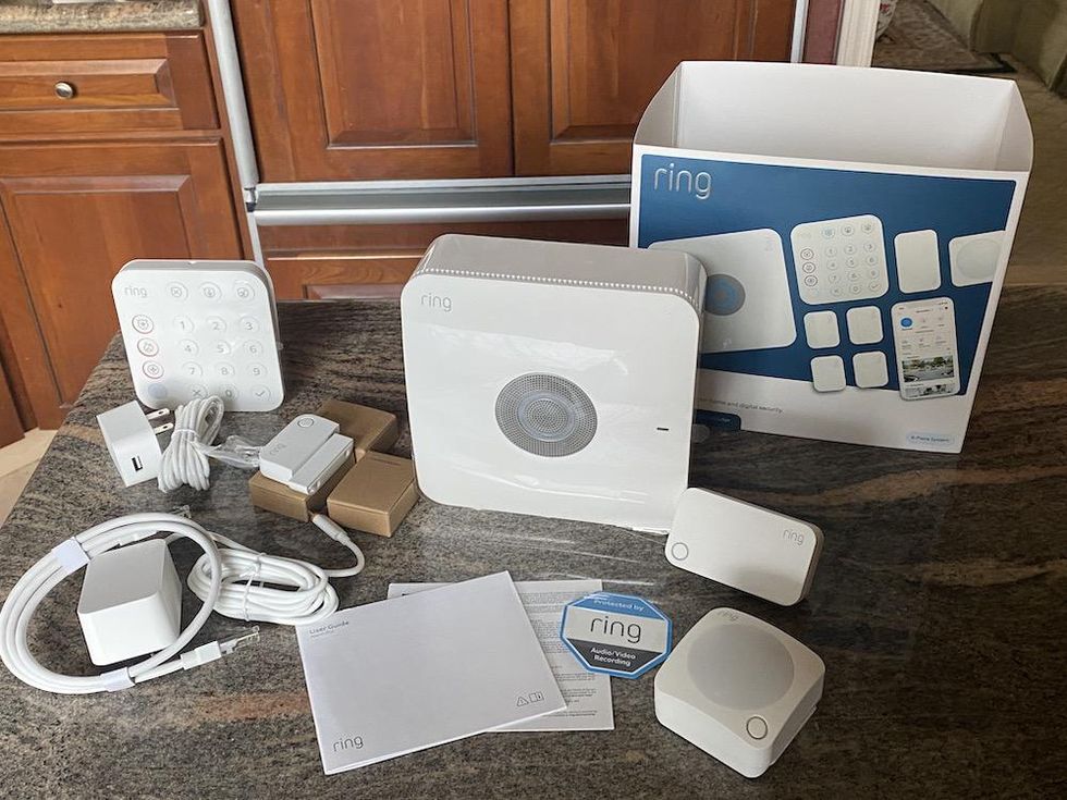 Foto do Kit de Segurança do Ring Alarm Pro, 8 peças com o roteador Eero Wi-Fi embutido em uma bancada unboxed