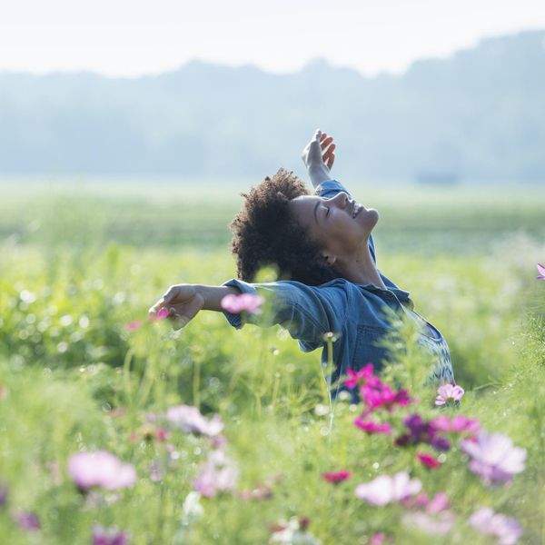 Woman in a field of flowers embracing her Saturn Return, self-mastery