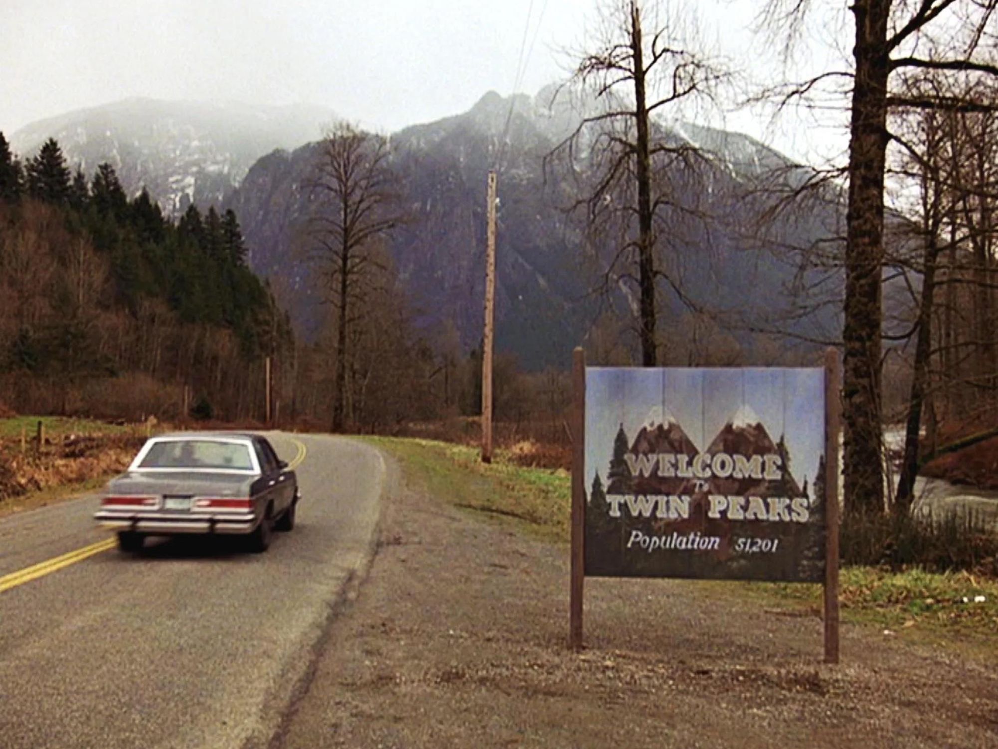 The opening roadside image from Twin Peaks with the town sign located beneath a mountainous vista