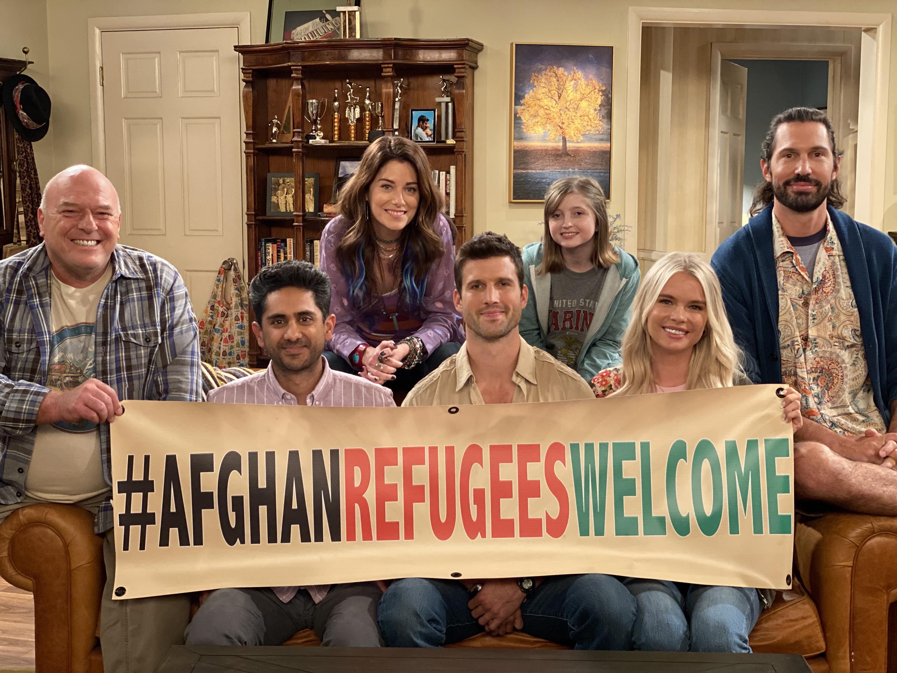 The cast of United States of Al holds up a sign proclaiming #afghanrefugeeswelcome