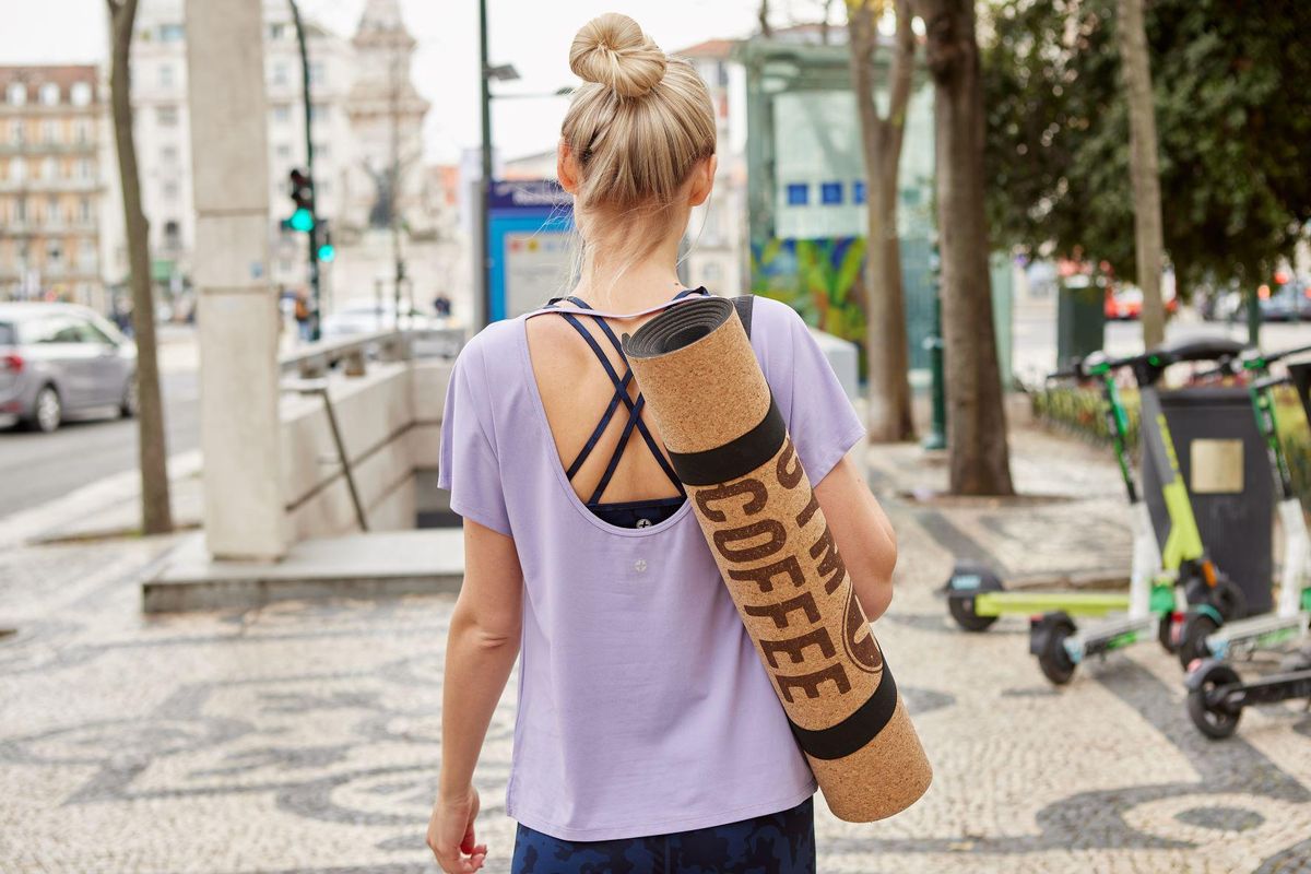 woman carrying gym+coffee yoga mat