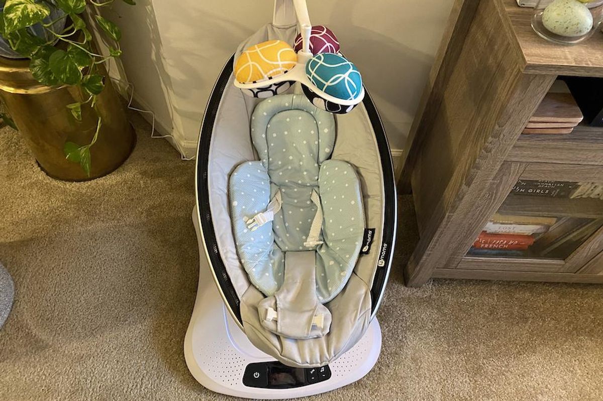 Photo of mamaroo4 Smart Swing in a living room with baby inserts.