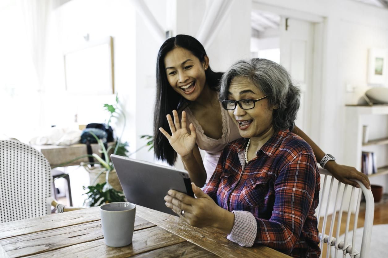 A photo of a mother and daughter making a facetime call on a tablet.