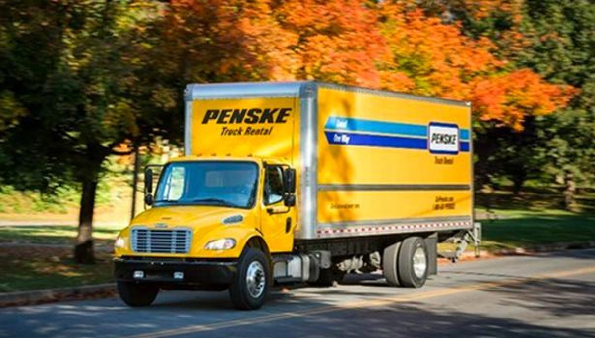 A Penske rental truck driving down the road. 