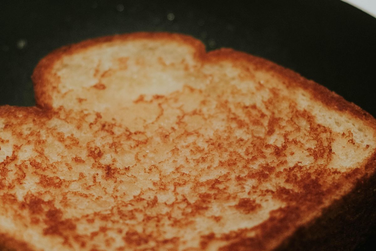 A grilled cheese in a frying pan all done.