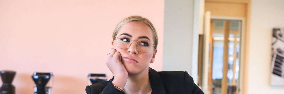 Woman looking frustrated while sitting at her desk with a laptop and a cup of coffee