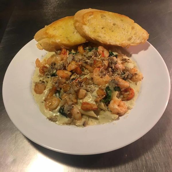 A white plate filled with penne pasta, cream sauce, shrimp and cheese.