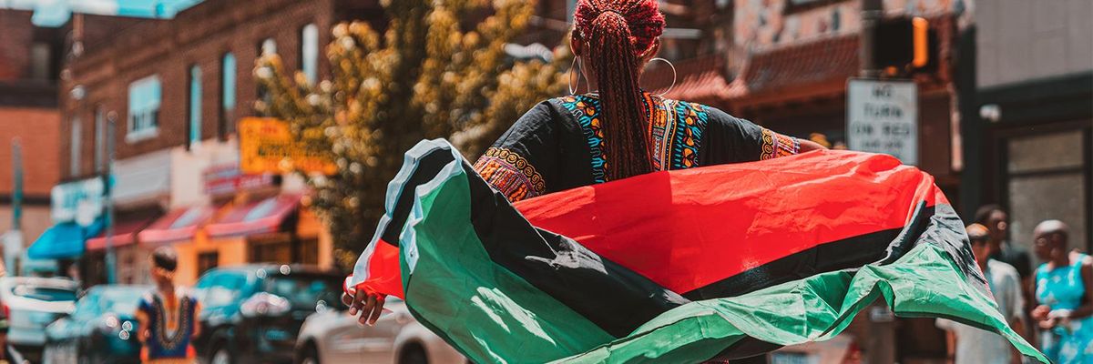 a woman holding a flag on a city street