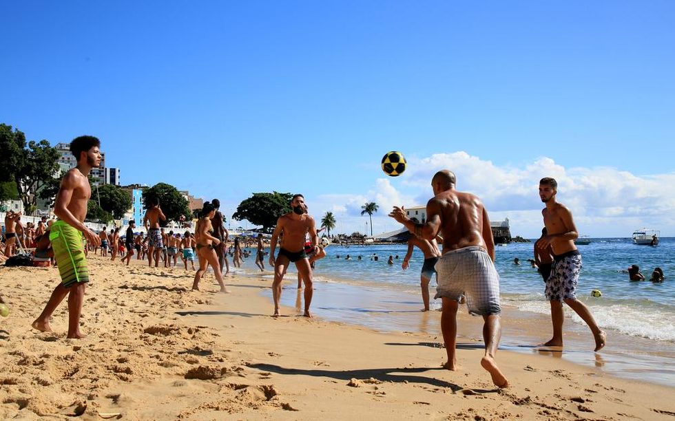 Group of people playing volleyball on crowded beach