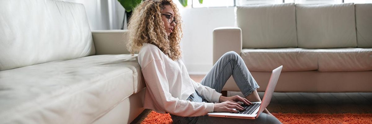 Woman sitting on the floor while reading from her laptop