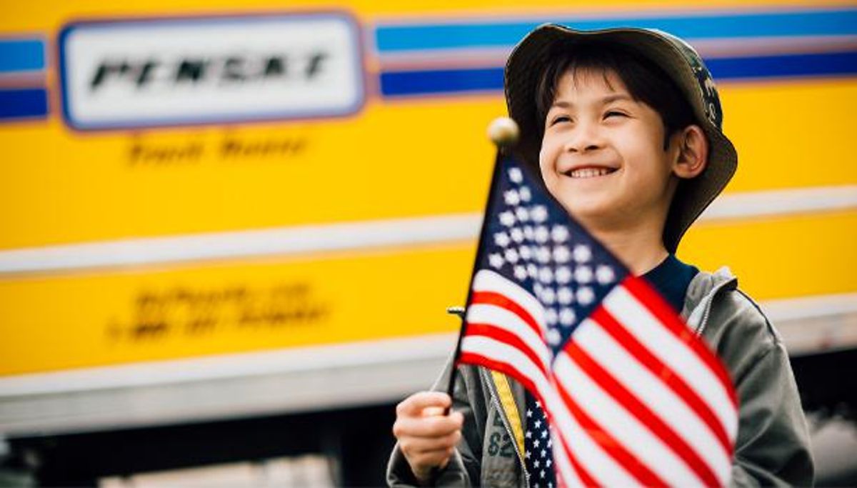 Boy holding American flag in front of a Penske truck.