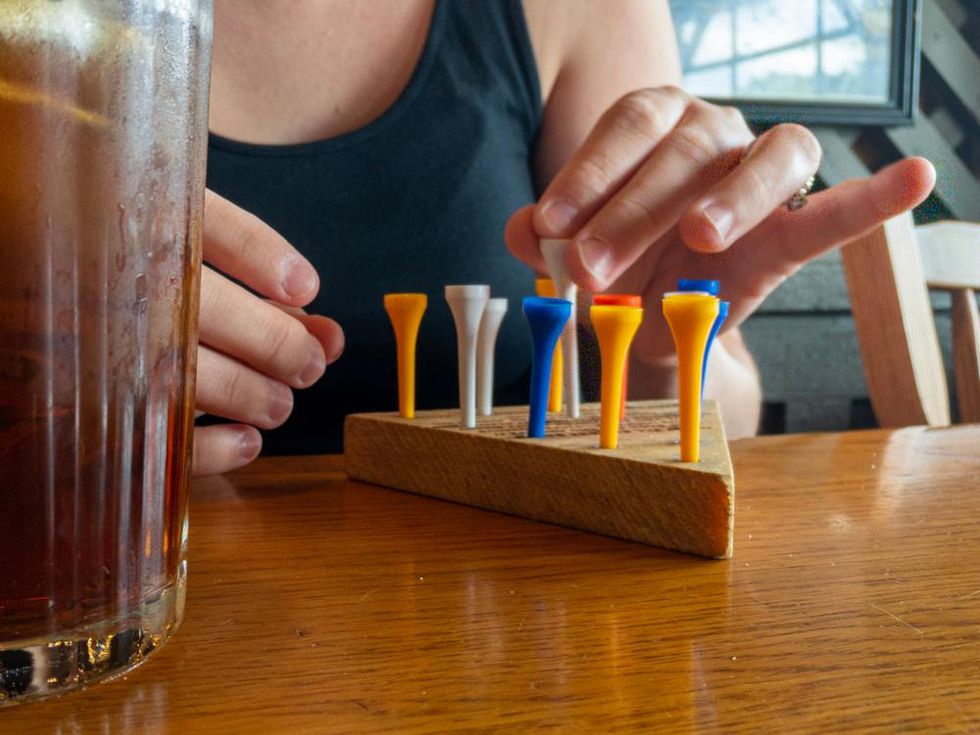 Photo of person playing peg game in Cracker Barrel with sweet tea on the left