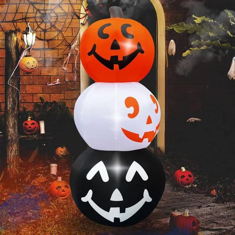 Inflatable on a porch with three pumpkins stacked. The bottom pumpkin is black; middle is white; top is orange.