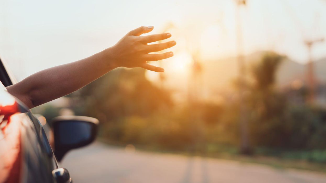 Hand reached outside car window as car is driving