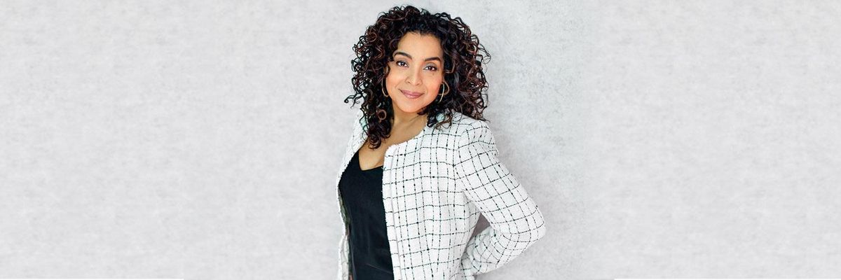 woman in business attire stands while looking at camera