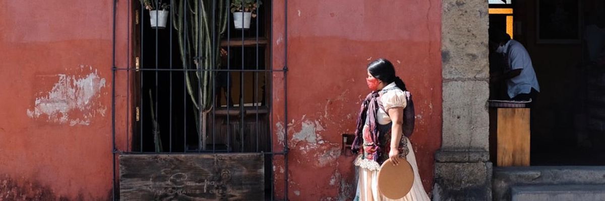 Girl holding clay tray walks down a street in Oaxaca