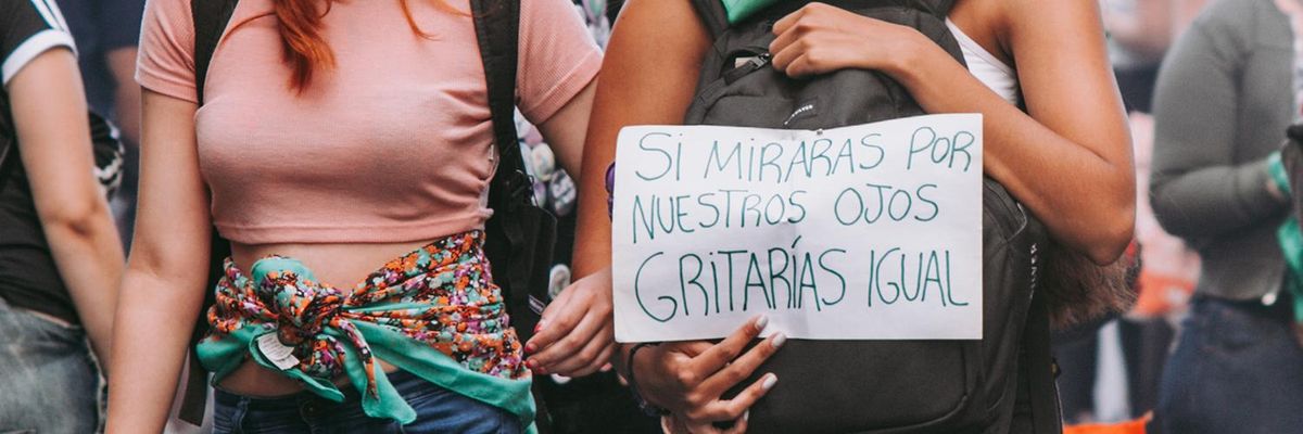 Two women at a protest holding up a sign that says: "Si miraras por nuestros ojos gritarías igual"