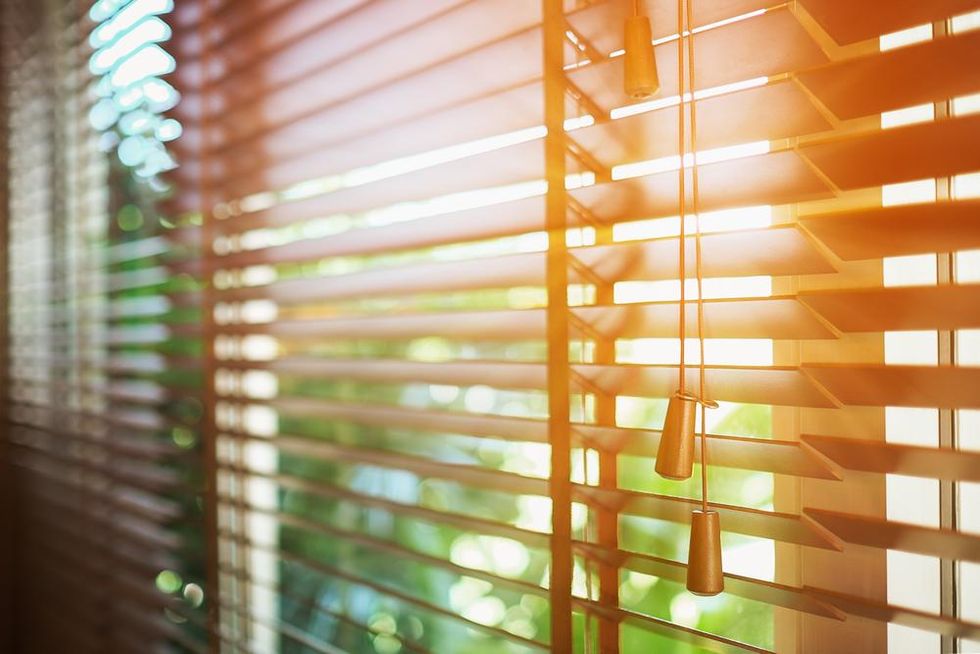 Blinds half open with sun rays filtering in