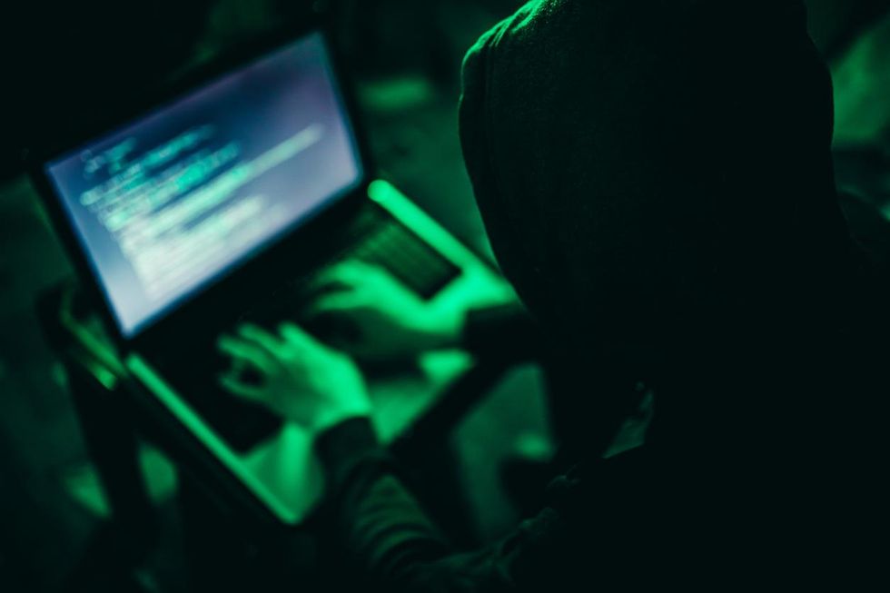 a photo of a hacker on a laptop at night