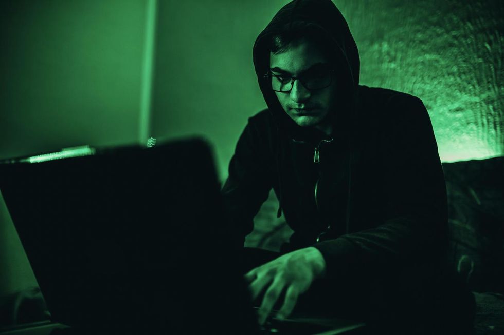 a hcaker at night on his laptop