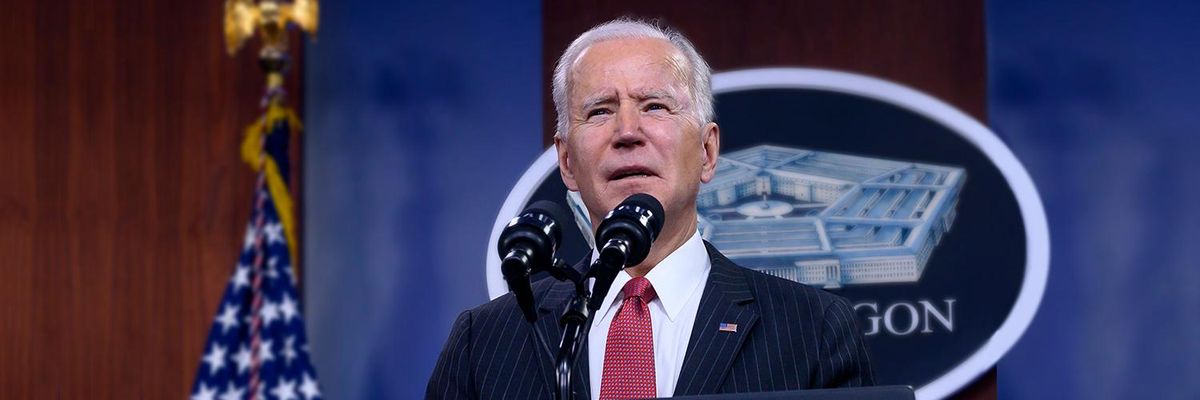 President Biden Stands at a Podium Speaking into Mics