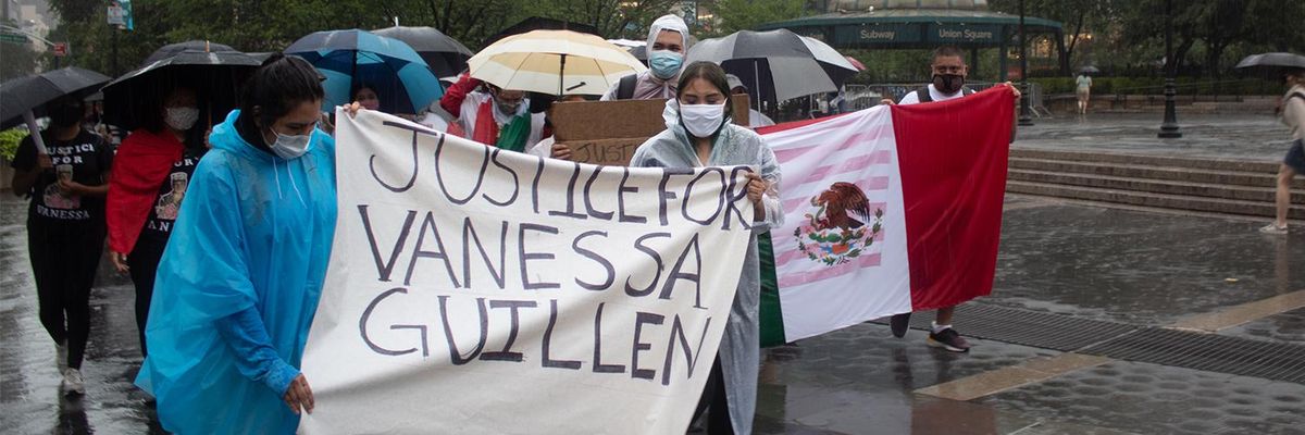 A group of protesters hold up a sign reading "Justice for Vanessa Guillen" while marching in the rain
