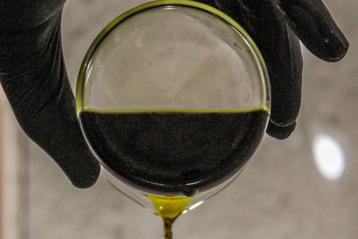 someone pouring black liquid out of a beaker