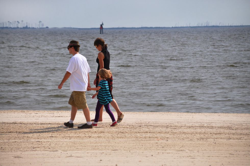 People walk on a Mississippi beach.